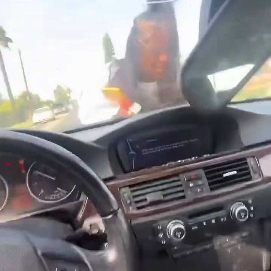 Man Speeds Away as Woman Clings to the Hood of His Car During Apparent Relationship Dispute